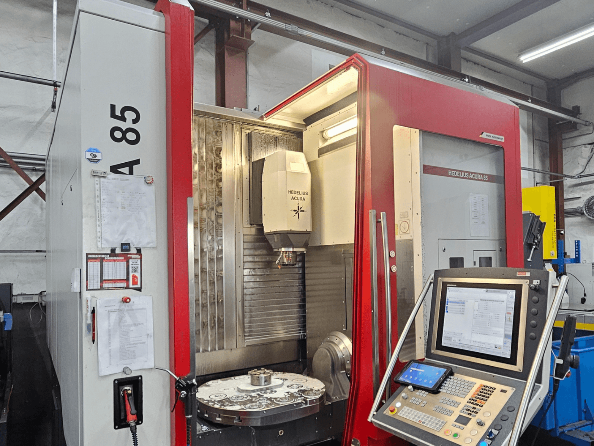 HEDLIUS Acura 85 vertikālais apstrādes centrs, skats no priekšpuses, ar vadības paneli un rotējošu galdu precīzai apstrādei.