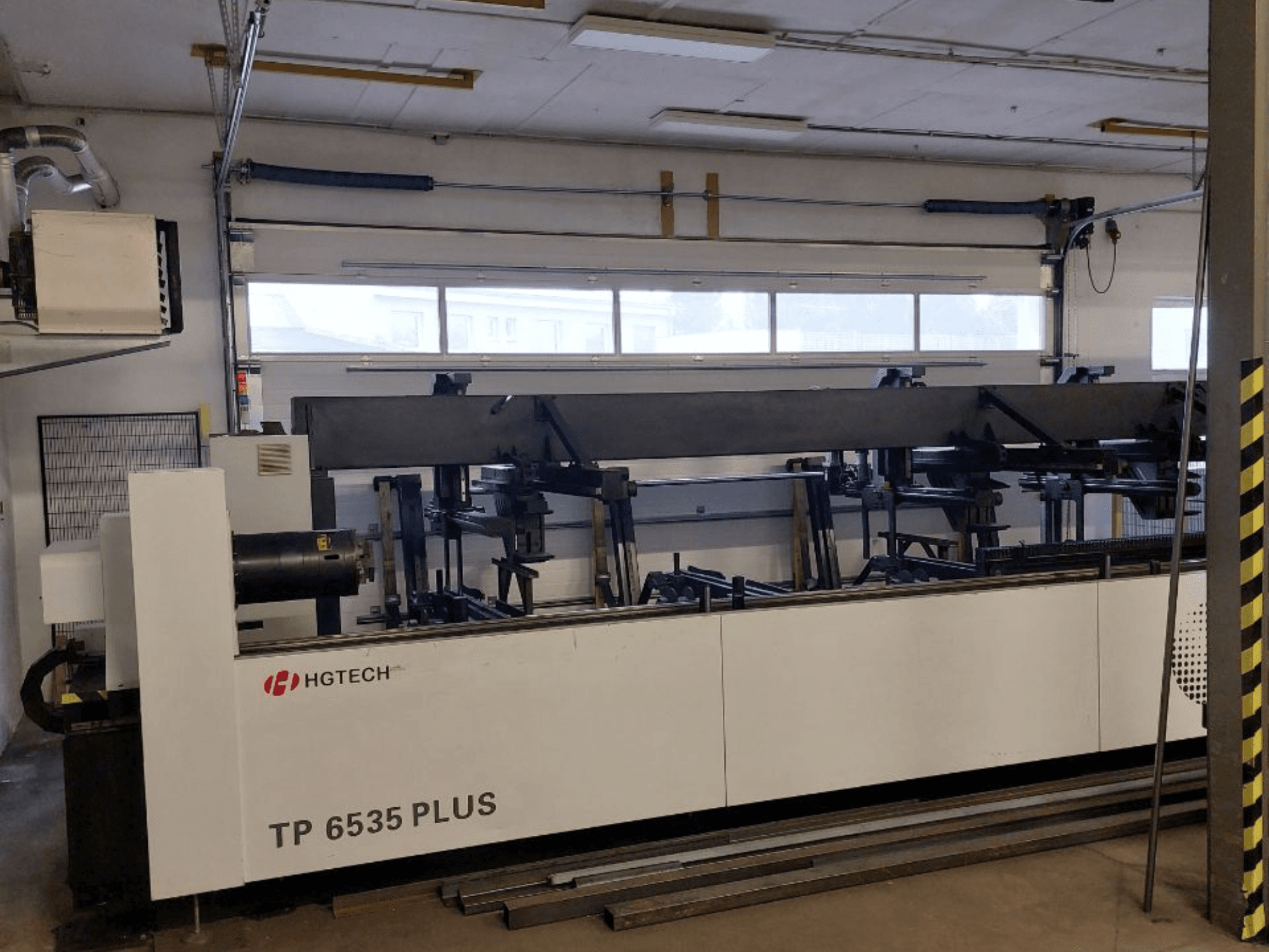 HGTECH TP 6535 PLUS, skats no priekšpuses uz lielu rūpniecisku mašīnu ar vairākām rokām precīzai ražošanai, kas uzstādīta darbnīcā.