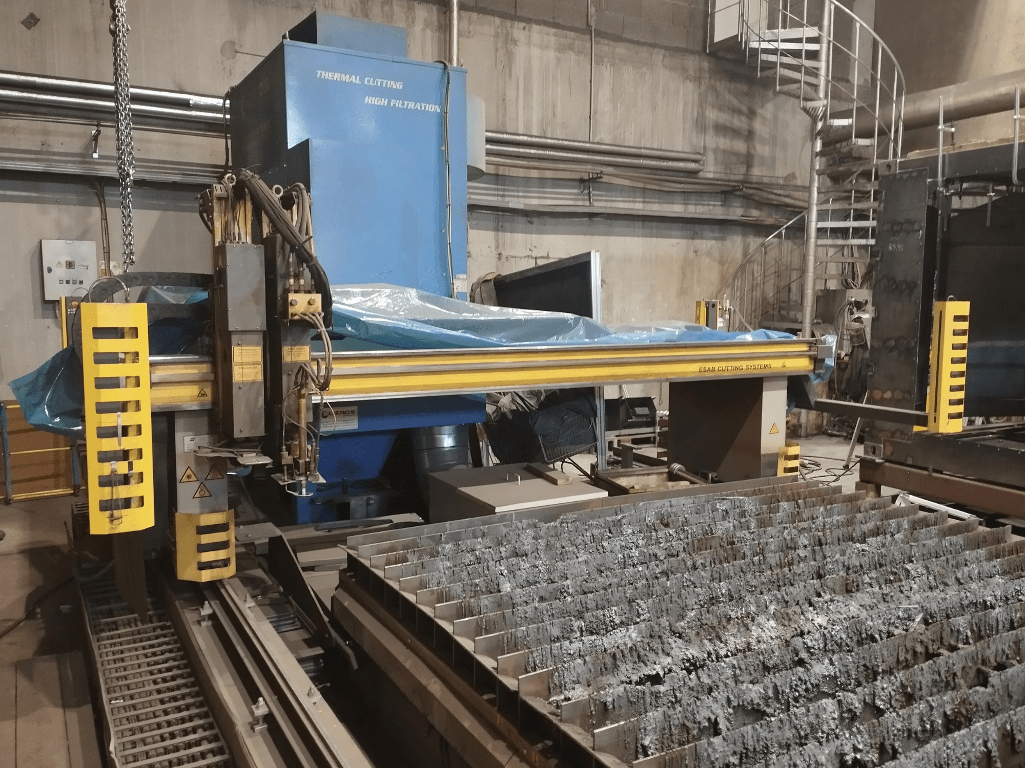 ESAB Combirex DX3500 Oxy plazmas griešanas iekārta, skats no priekšpuses, ar dzelteniem drošības elementiem un metāla griešanas galdu.