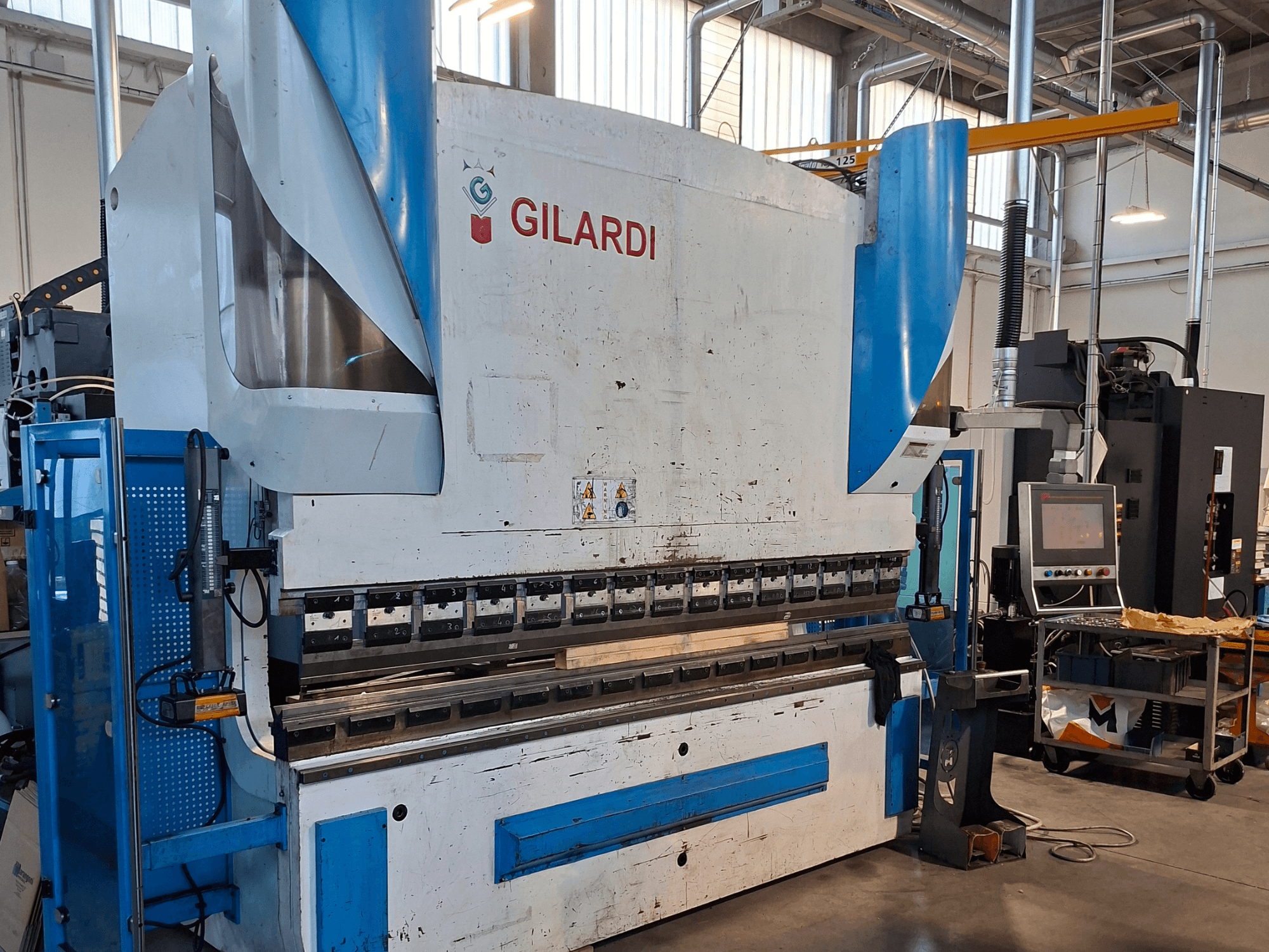 GILARDI Itālija 3,25 hidrauliskā prese, skats no priekšpuses, kurā redzamas vadības ierīces un ražošanas vides detaļas.