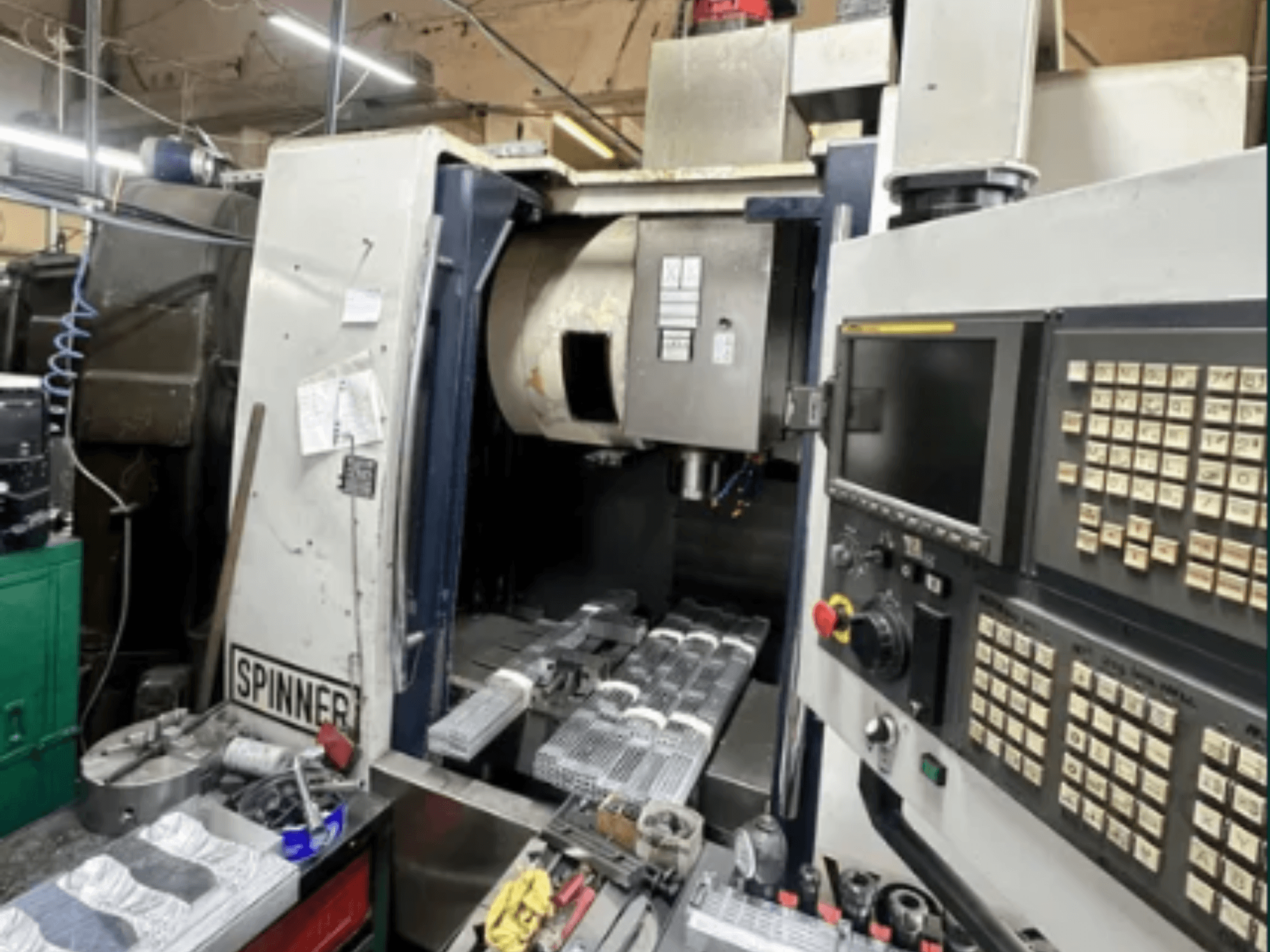 CNC mašīna Spinner, skats no priekšpuses; skārienjūtīgā ekrāna saskarne, instrumenti darba laukumā un apstrādei sagatavotas detaļas.