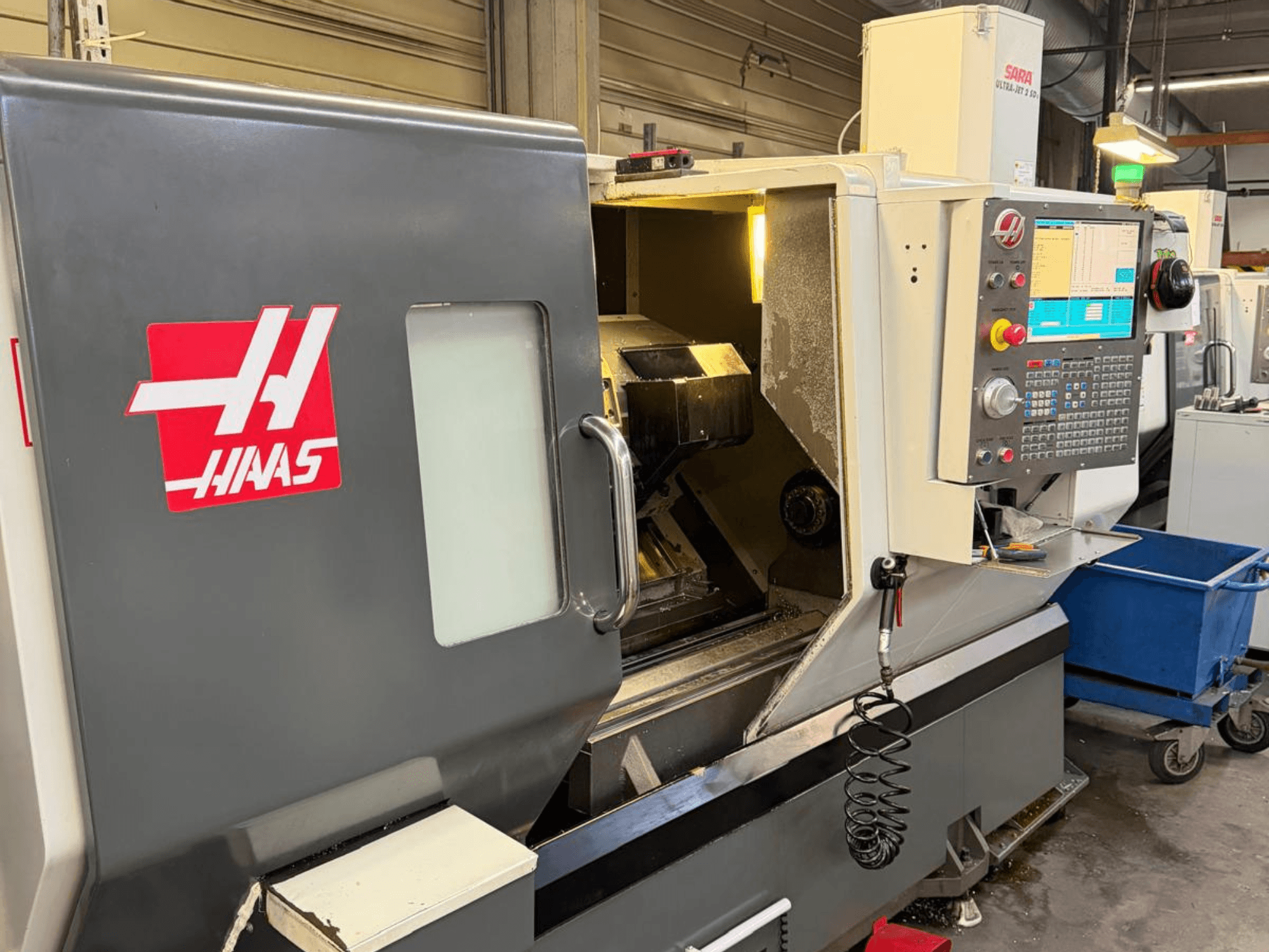 HAAS DS-30SSY horizontālās virpošanas iekārta, priekšējais skats, ar redzamu vadības paneli un iekšējām detaļām, darbnīcā.