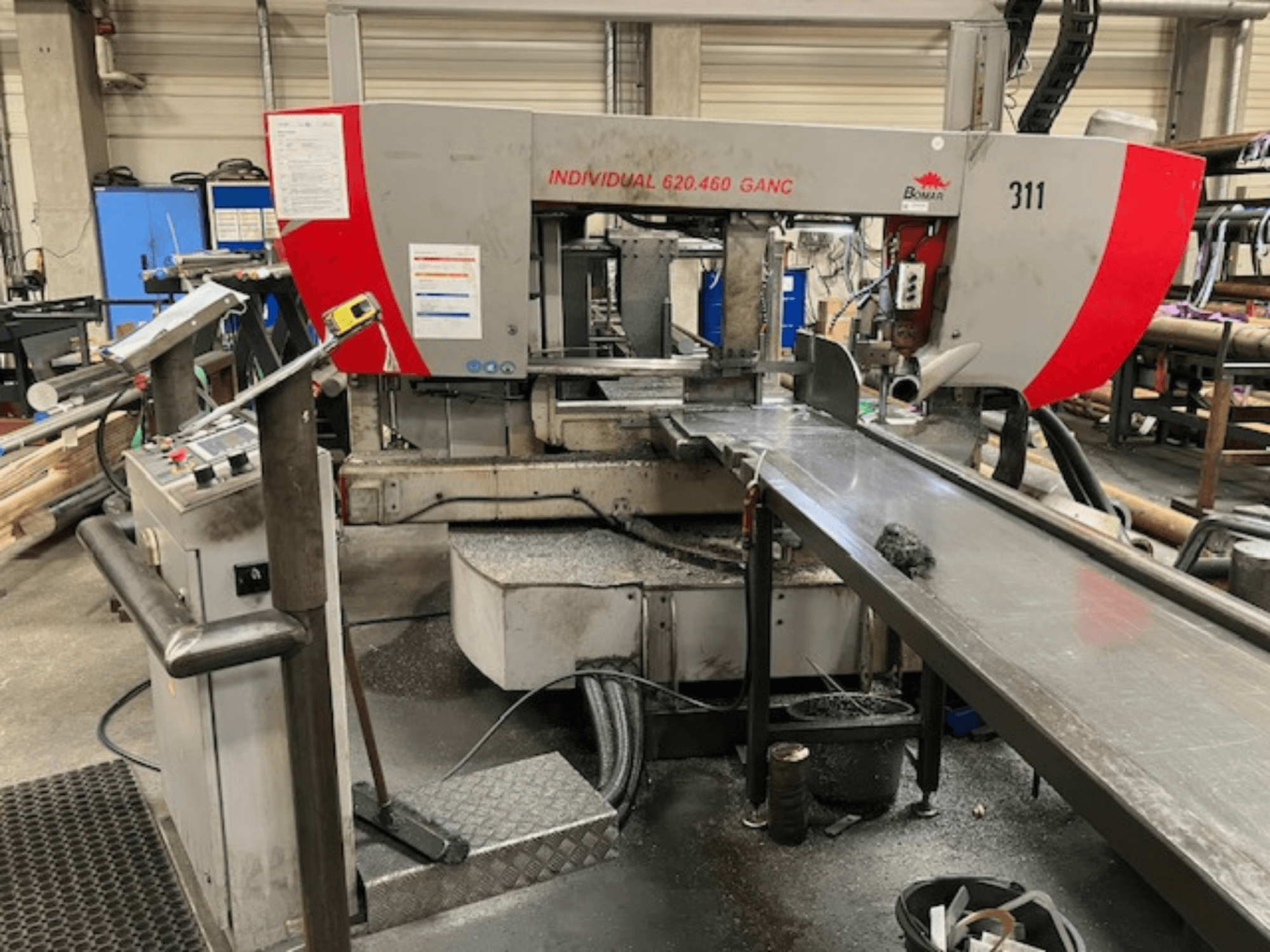 BOMAR INDIVIDUAL 620-460 GANC lentzāģis, skats no priekšpuses, redzamas vadības ierīces, griešanas zona un rūpnieciskās darbnīcas fons.
