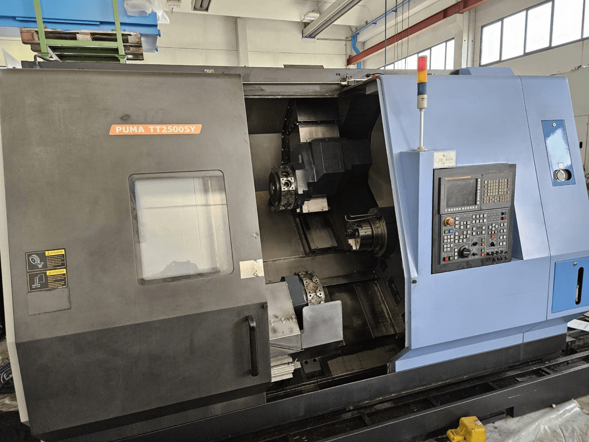 DOOSAN PUMA TT2500SY daudzspindeles virpošanas stends, skats no priekšpuses, kurā redzams vadības panelis un stenda iekšējās detaļas.