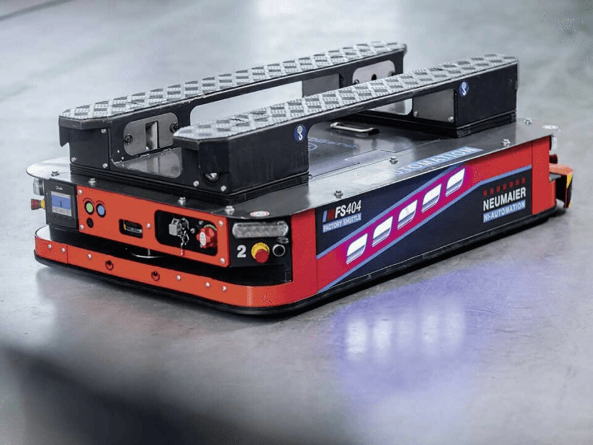 NEUMAIER AGV Factory Shuttle FS404, zema profila palešu pārvietošanas sistēma, sānu skats, kurā redzami riteņi, vadības un drošības elementi.