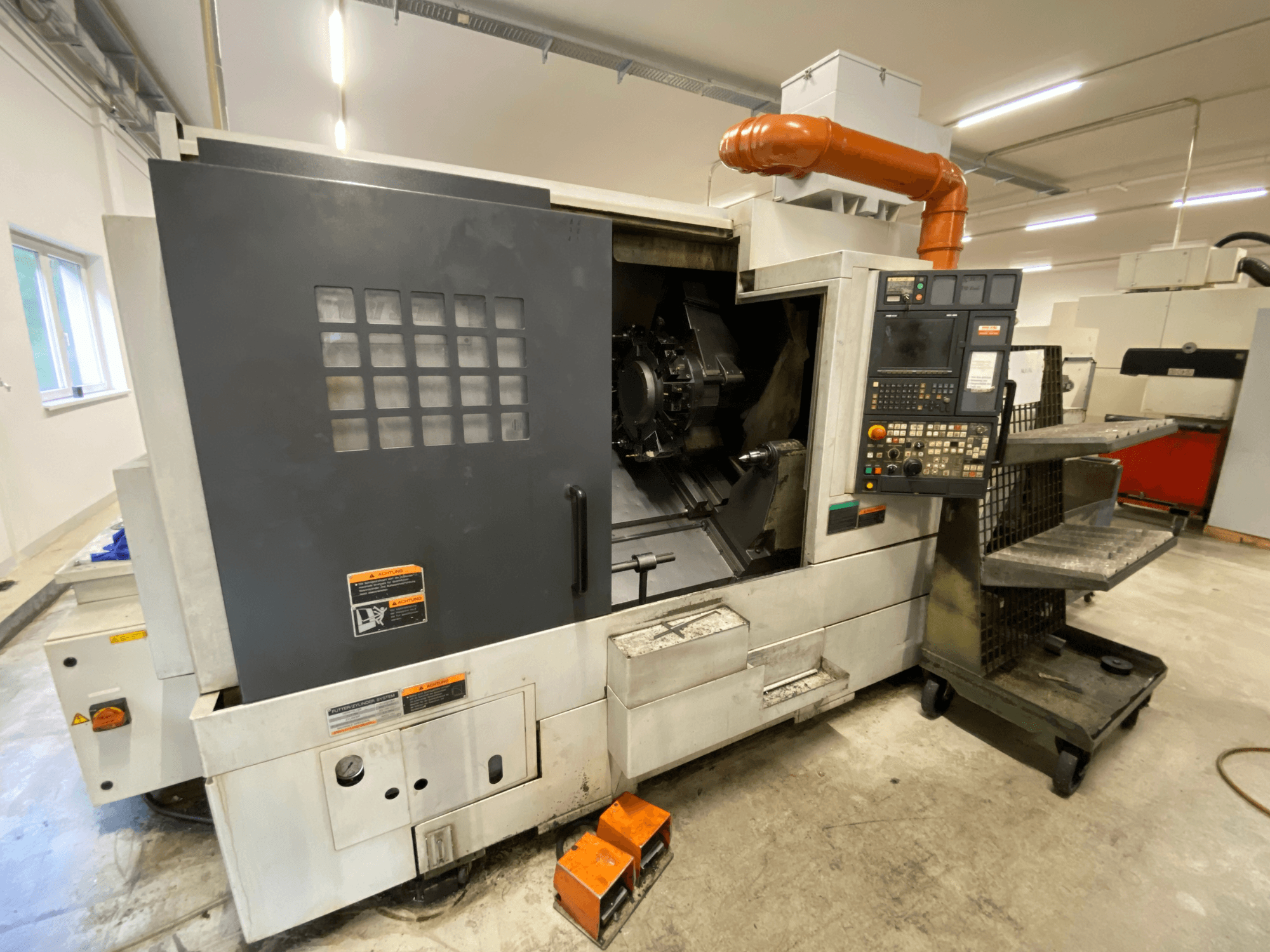 DMG Mori Seiki NL2500Y/700 virpošanas un frēzēšanas centrs, skats no priekšpuses, kurā redzama vadības pults un stenda detaļas.