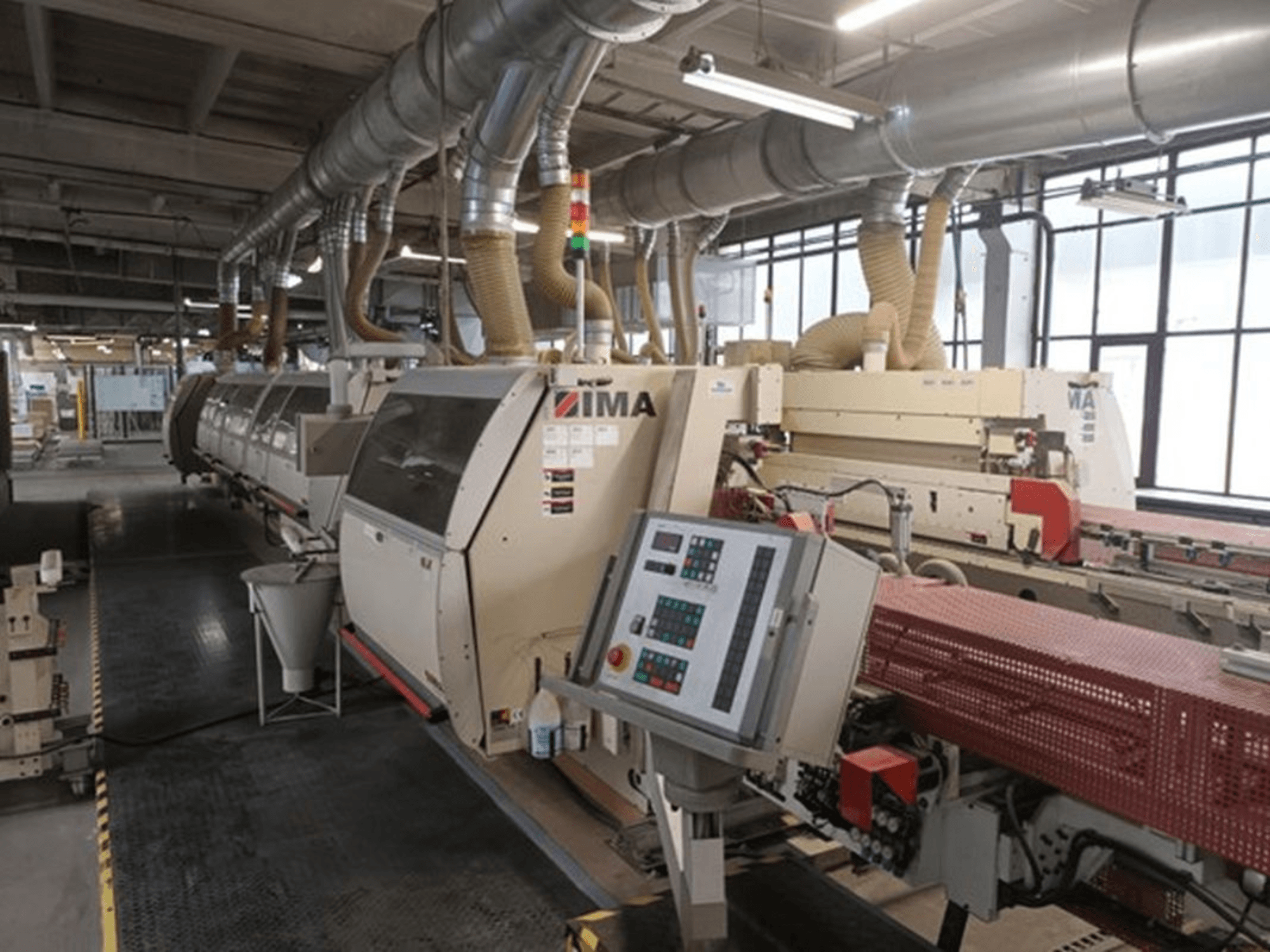 IMA rūpnieciskās iekārtas rūpnīcā, skats no priekšpuses, ar vadības paneļiem un putekļu nosūces caurulēm.