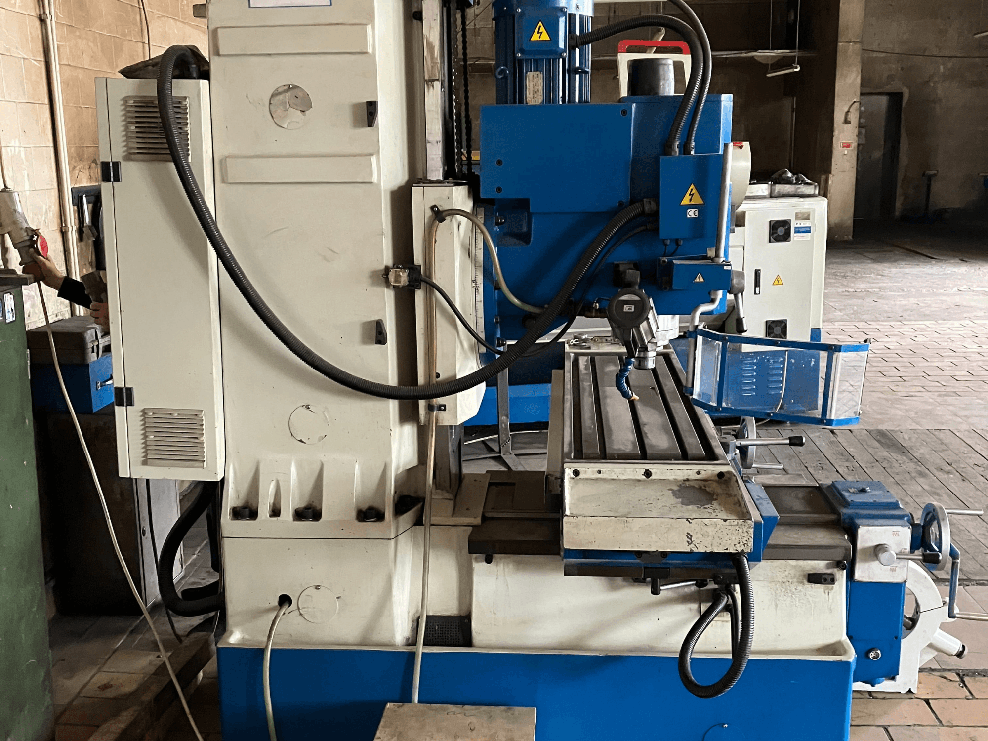 Vertikālais apstrādes centrs KNUTH KB 1400, skats no priekšpuses, kurā redzams vadības panelis, griešanas instruments un darba galds ar lineārām sliedēm.