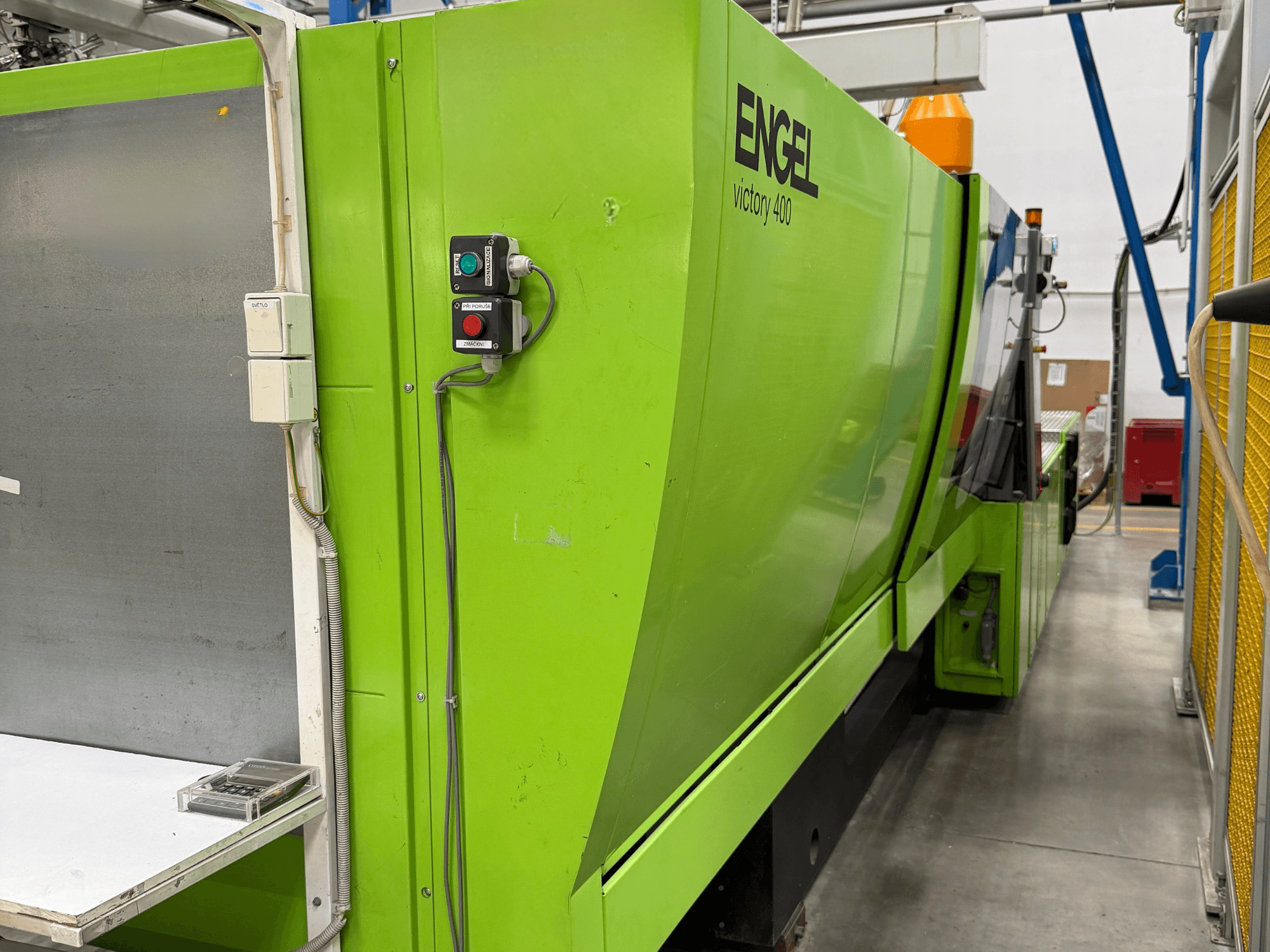Hidrauliskā plastmasas liešanas mašīna „Engel Victory 400“, skats no sāniem, ar vadības paneli un zaļu korpusu.