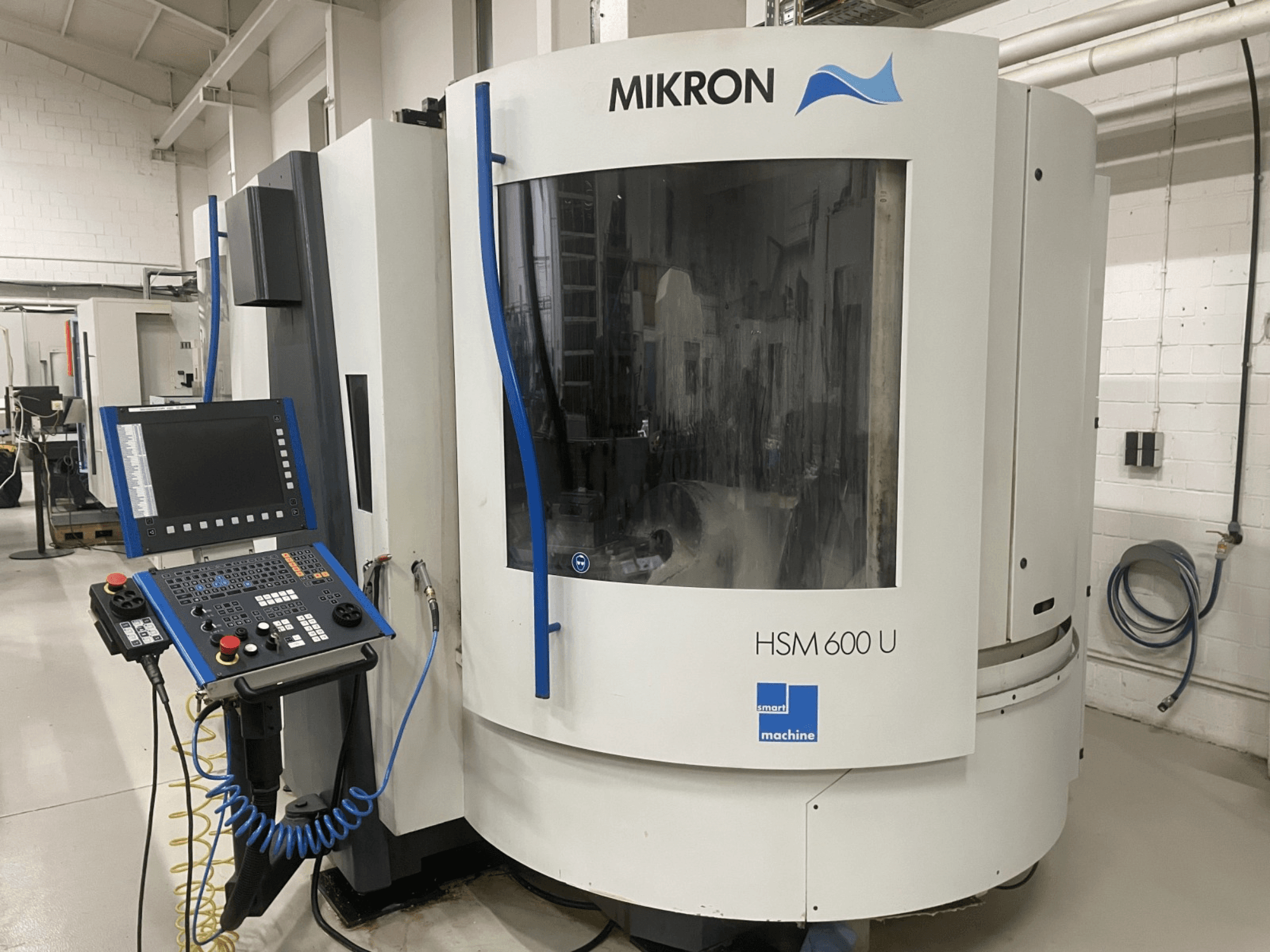 MIKRON HSM600U vertikālais apstrādes centrs no priekšpuses ar operatīvo vadības paneli un lielu skatu logu.