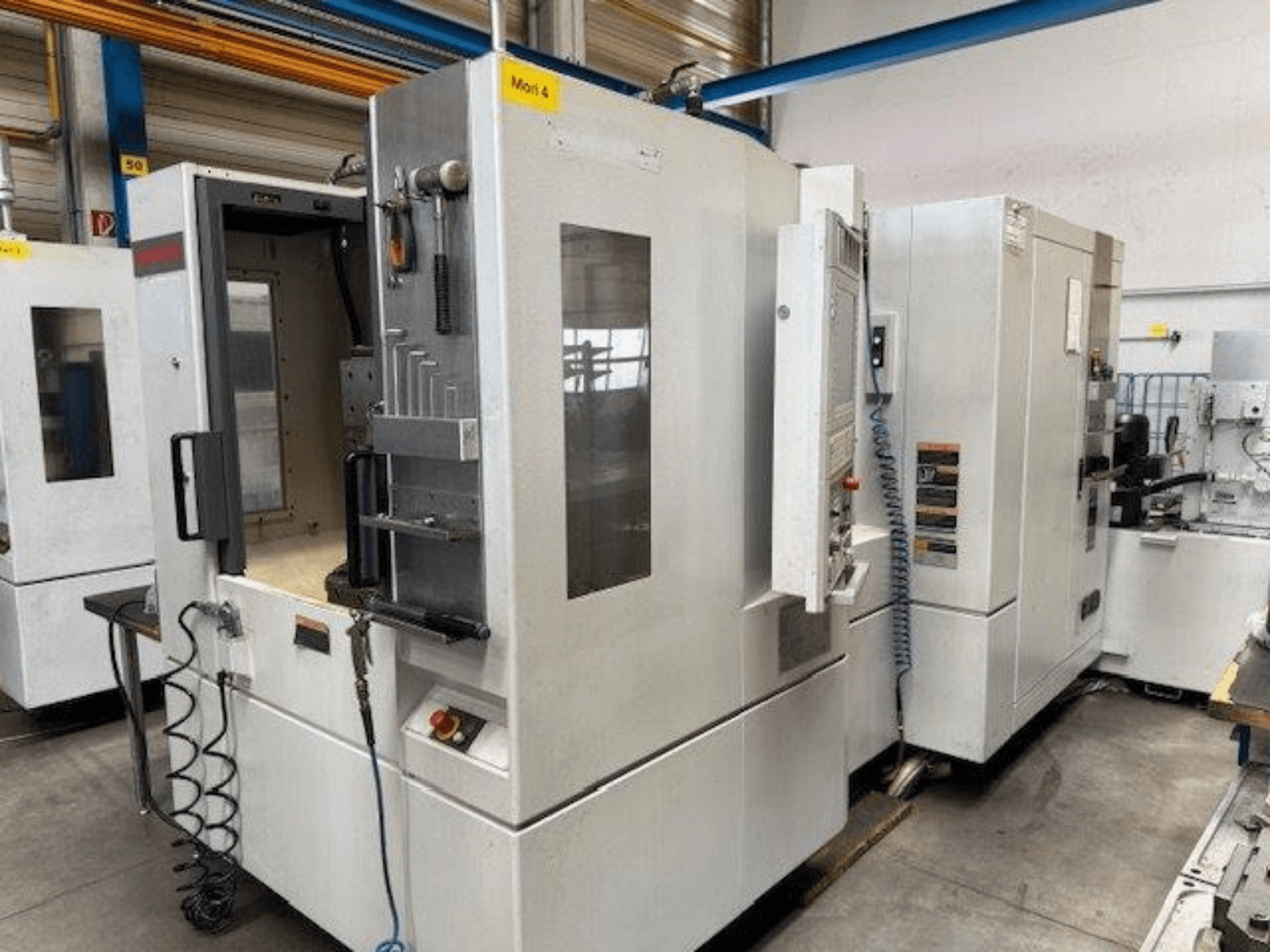 MORI SEIKI NH4000 DCG horizontālais apstrādes centrs no priekšpuses ar atvērtām durvīm un vadības paneļa detaļām.