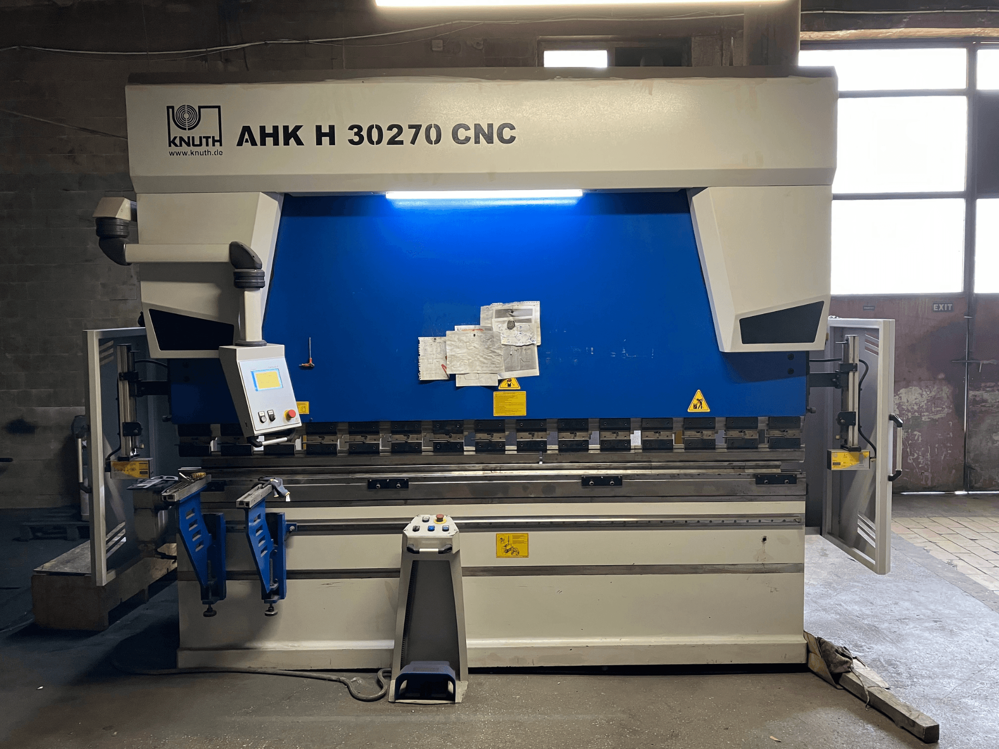 KNUTH AHK H 30270 CNC leņķspiedes stends darbnīcā, skats no priekšpuses, kurā redzams vadības panelis un zils/balts dizains, ar atvērtām sānu durvīm.