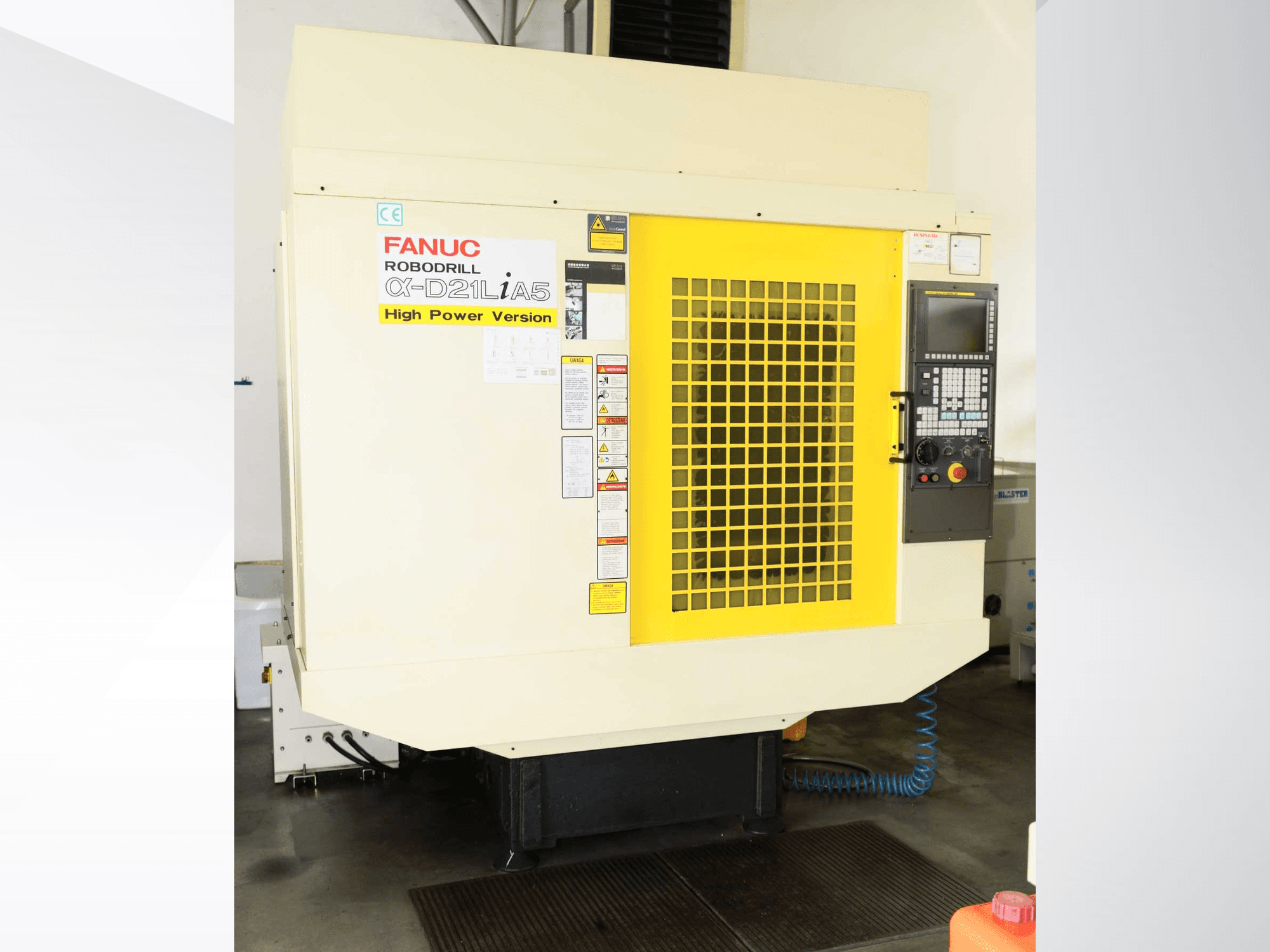 FANUC ROBODRILL α-D21LiA5 vertikālais apstrādes centrs, skats no priekšpuses ar dzelteno drošības režģi un vadības paneļa detaļām.