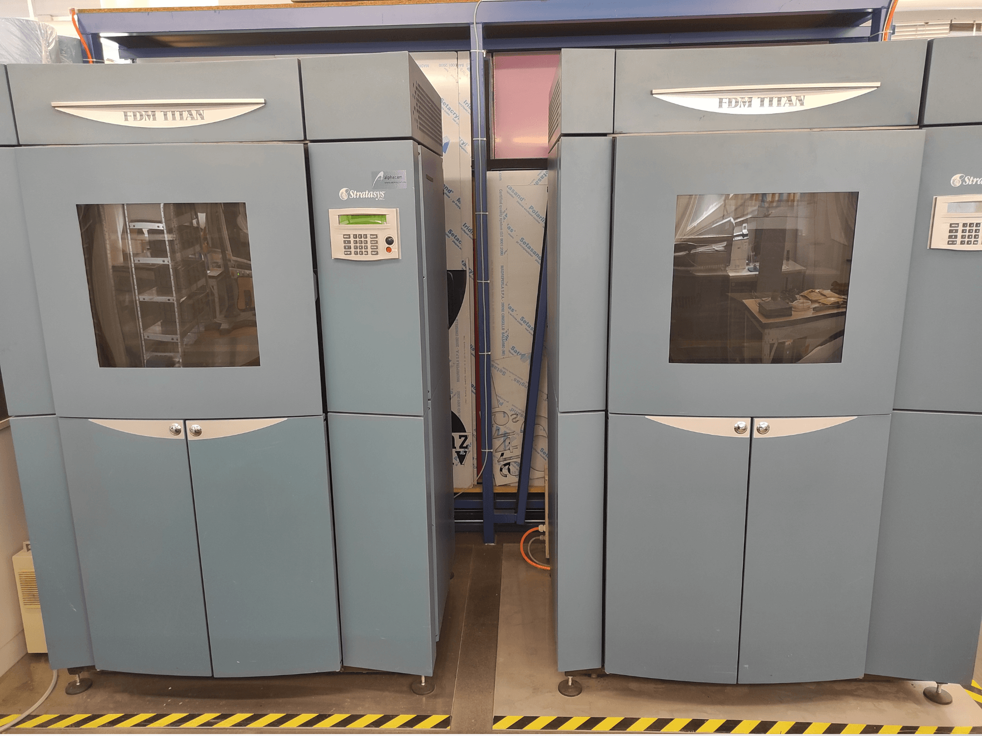 Stratasys FDM TitanTI T0031 plastmasas 3D printera skats no priekšpuses; tam ir displejs un caurspīdīgs logs.