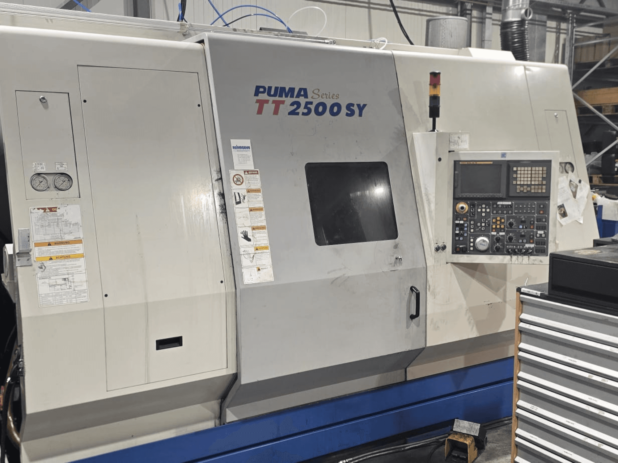 PUMA sērijas TT 2500 SY CNC virpa, skats no priekšpuses; redzams vadības panelis ar ciparnīcām un pogām, mērinstrumenti un darbības etiķetes.
