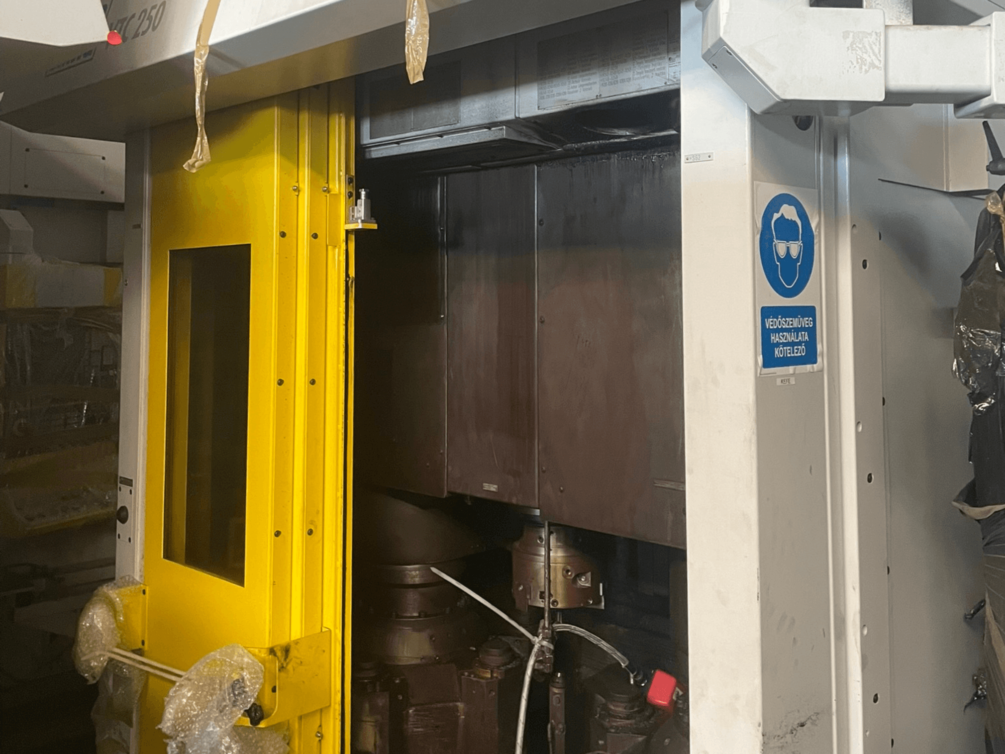 Dzeltenas mašīnas ieejas durvis ar drošības zīmi, Z250 modeļa rūpnieciskās mašīnas priekšējais skats, parādot iekšējās sastāvdaļas.