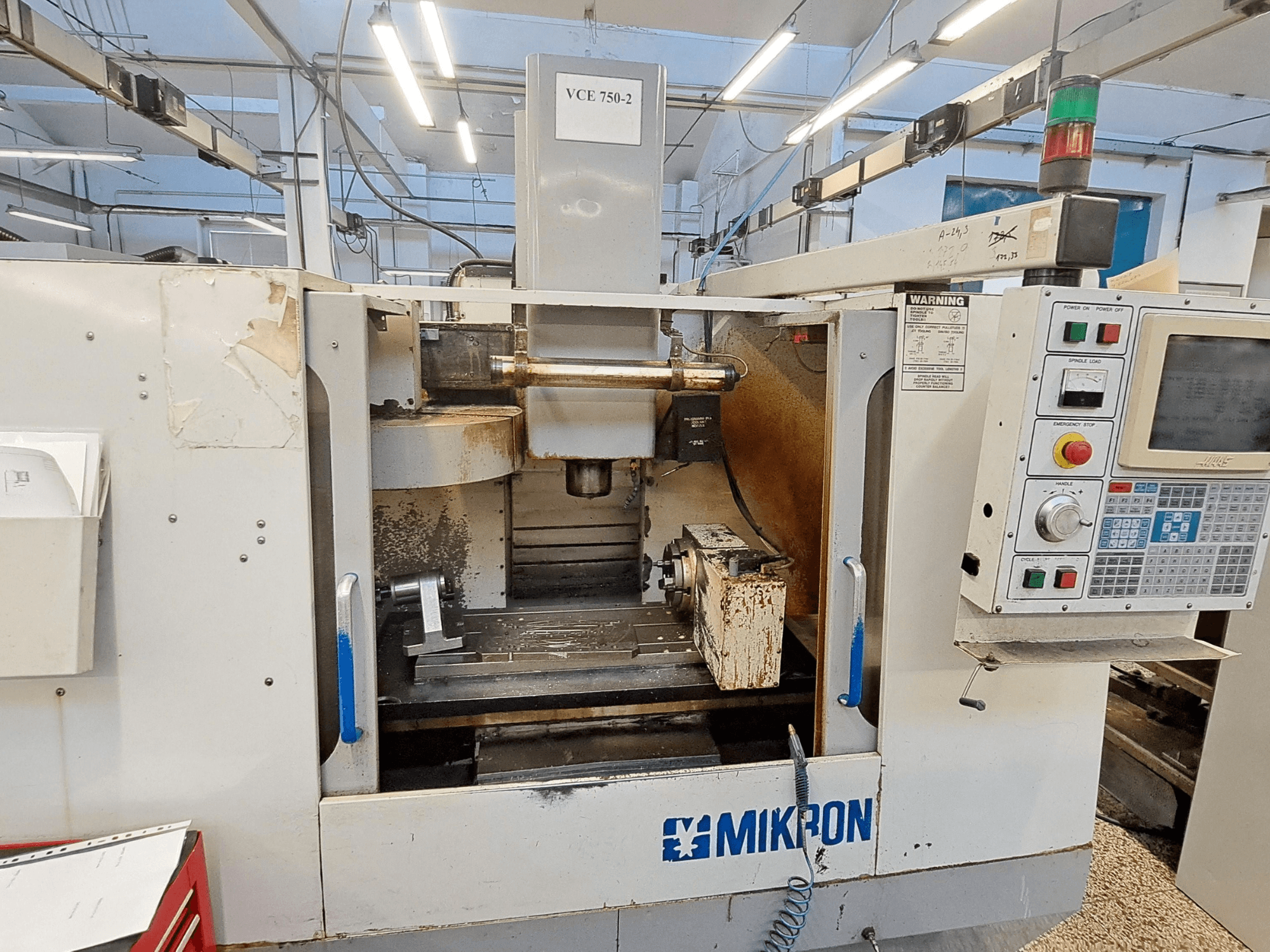 Mikron VCE 750-2 CNC frēzmašīna, priekšējais skats, ar vadības paneli un vārpstu apstrādes zonā, redzams nolietojums un netīrumi.