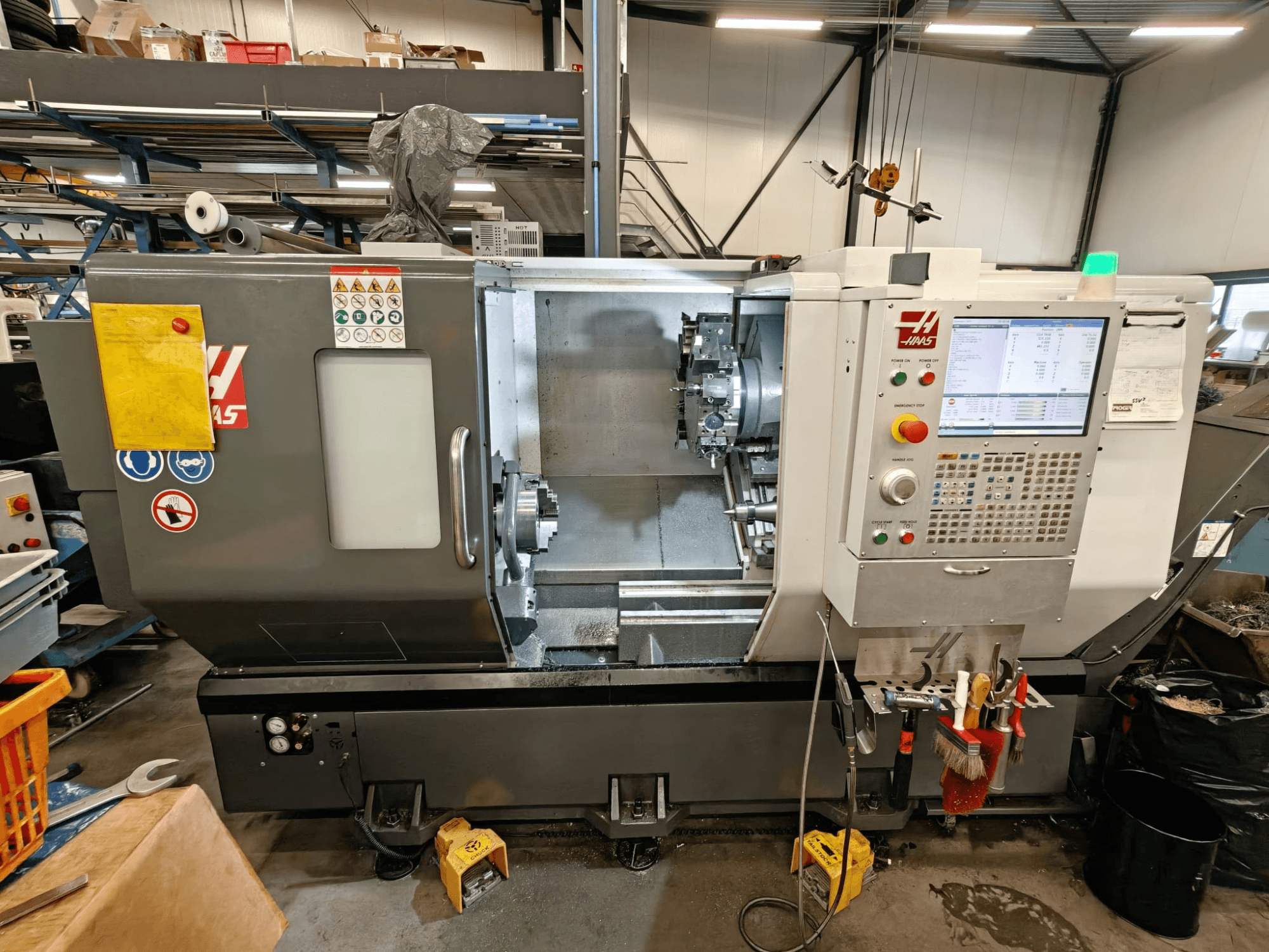 HAAS ST-25Y horizontālās virpošanas darbgalds, skats no priekšpuses, kurā redzams vadības panelis, instrumentu glabāšanas vieta un darba iestatījumi darbnīcā.