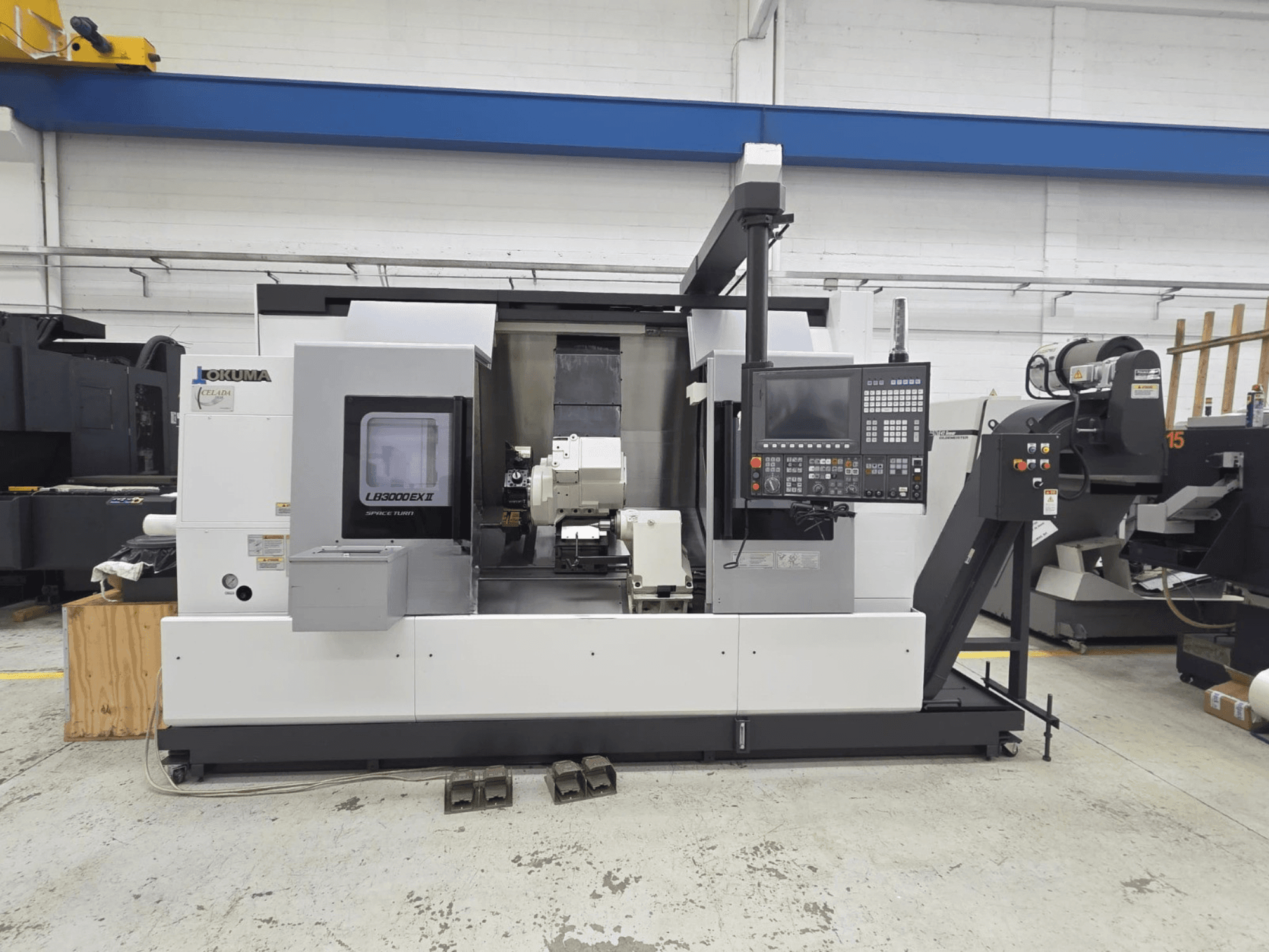 Okuma LB 3000 EXII horizontālās virpošanas darbgalds priekšpusē ar vadības paneli un instrumentu turētāju.