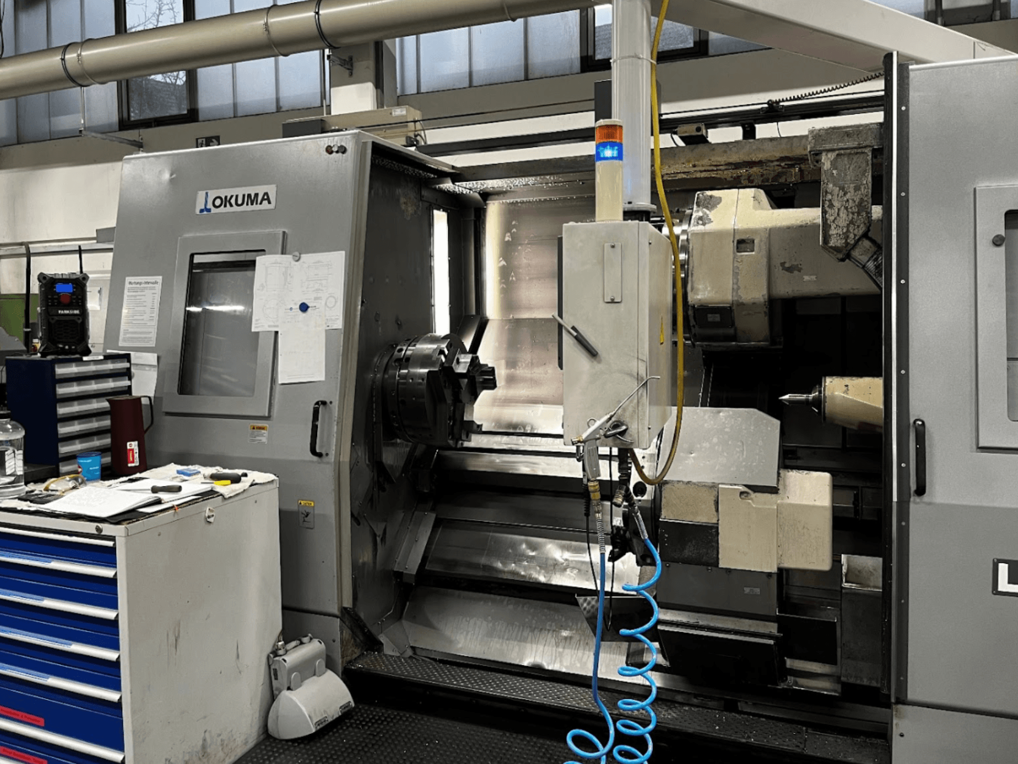 Okuma LU35-M horizontālās virpošanas iekārta, skats no priekšpuses. Vadības panelis, darbarīki un liels turētājs apstrādes operācijām.