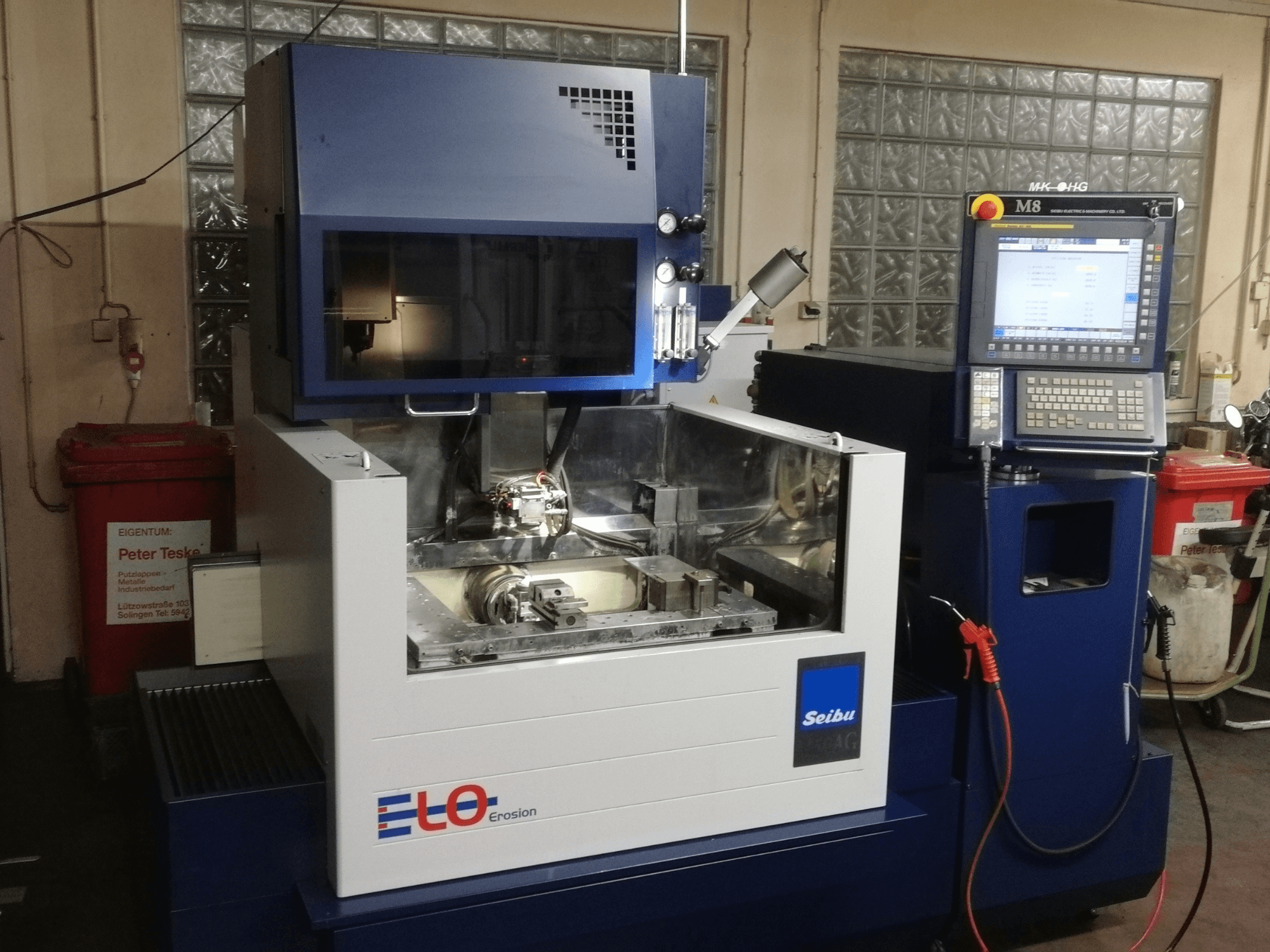 ELO Seibu erozijas mašīna no priekšpuses ar vadības paneli un redzamu darba zonu ar metāla komponentiem.